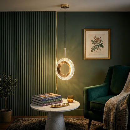 Round ring crystal gold LED pendant light beside an emerald velvet armchair in a reading corner