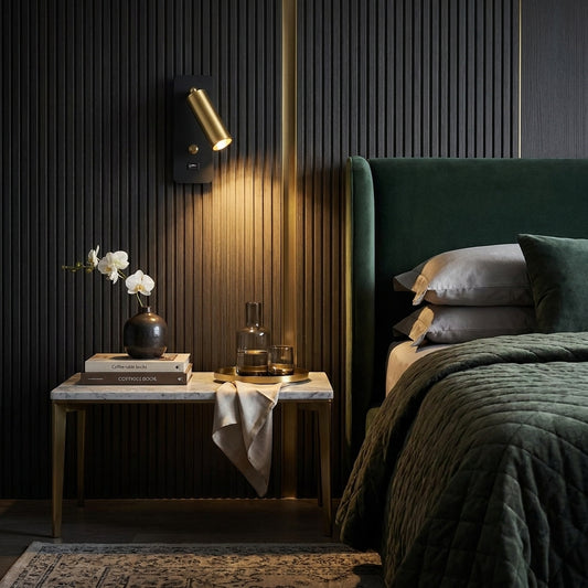 Black and brass USB reading wall light in a luxurious dark green bedroom with marble nightstand